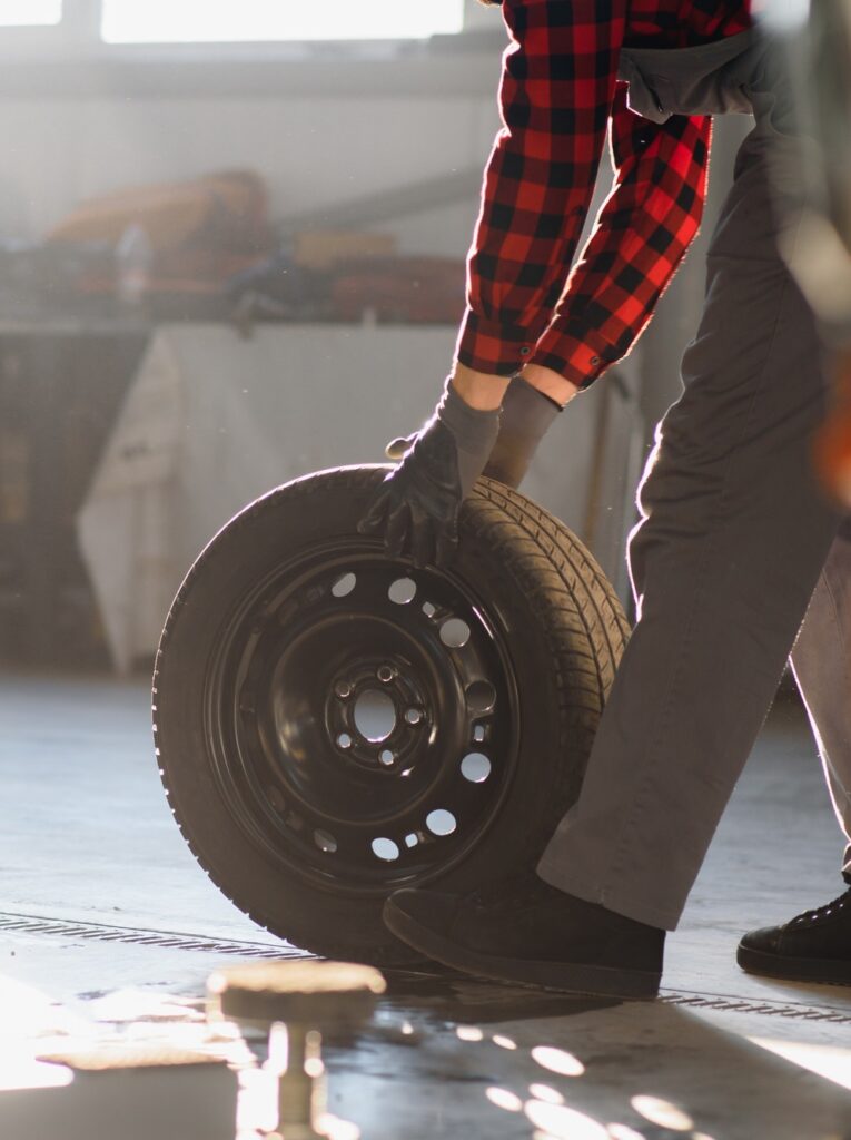 Mechanic holding a tire tire at the repair garage. replacement of winter and summer tires.